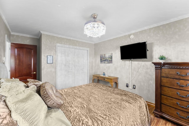 bedroom with wood finished floors, a closet, baseboards, a chandelier, and ornamental molding
