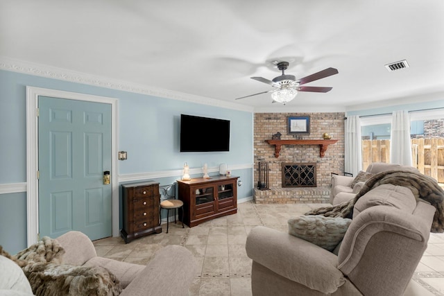 living area with a ceiling fan, a fireplace, and ornamental molding