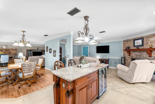 kitchen with open floor plan, wine cooler, brown cabinets, light stone counters, and arched walkways