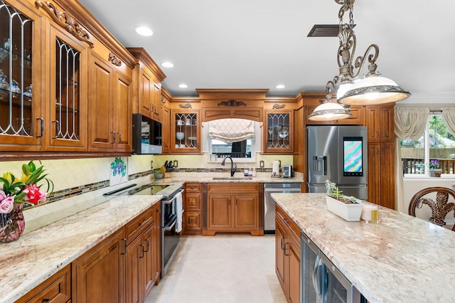 kitchen featuring stainless steel appliances, a sink, light stone counters, brown cabinets, and recessed lighting