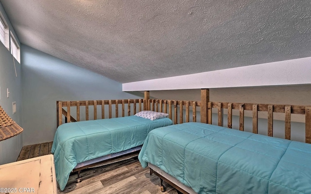 bedroom with wood finished floors, a textured ceiling, and lofted ceiling