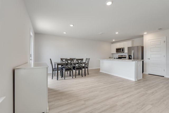 kitchen with recessed lighting, appliances with stainless steel finishes, light wood-style floors, and white cabinetry