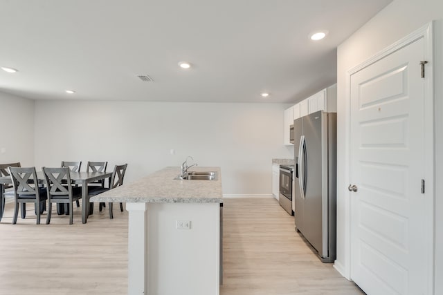 kitchen featuring a sink, light wood-style floors, stainless steel refrigerator with ice dispenser, white cabinetry, and light countertops