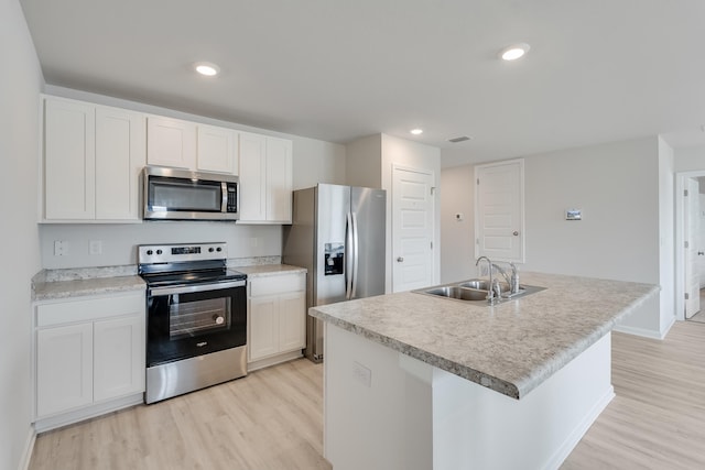 kitchen with white cabinetry, light wood-style flooring, a sink, appliances with stainless steel finishes, and baseboards