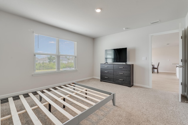 bedroom featuring baseboards, visible vents, and light carpet