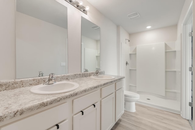 bathroom featuring toilet, a stall shower, and a sink