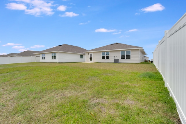 back of house with fence, a yard, and central air condition unit