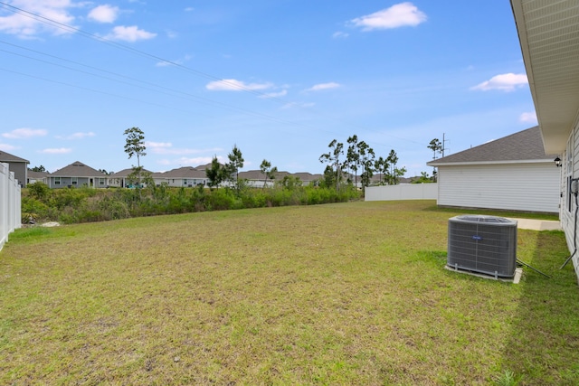 view of yard featuring fence, a residential view, and central air condition unit