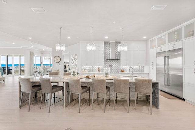320 Harbor Blvd Unit 1201, Destin, FL 32541 - kitchen featuring wall chimney range hood, a large island with sink, built in fridge, a sink, and a notable chandelier