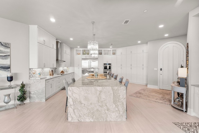 320 Harbor Blvd Unit 1201, Destin, FL 32541 - kitchen with wall chimney exhaust hood, stainless steel appliances, white cabinetry, recessed lighting, and visible vents