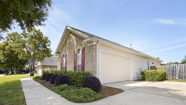 174 Mango Ln, Freeport, FL 32439 - view of side of home featuring fence, brick siding, a garage, and concrete driveway