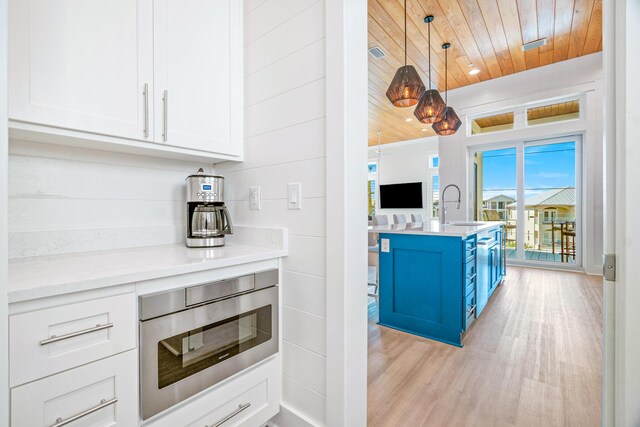40 Cote D Azur Dr, Santa Rosa Beach, FL 32459 - kitchen with stainless steel microwave, a sink, light wood-style floors, wooden ceiling, and blue cabinetry