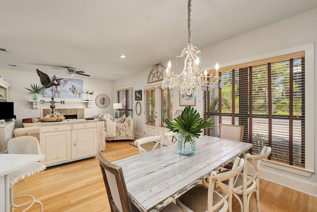 16 Kingfish St, Santa Rosa Beach, FL 32459 - dining area with a tile fireplace, light wood finished floors, a chandelier, recessed lighting, and a ceiling fan