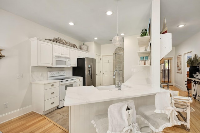 16 Kingfish St, Santa Rosa Beach, FL 32459 - kitchen featuring white appliances, a peninsula, white cabinets, a sink, and light wood-type flooring