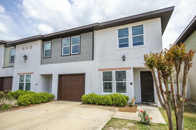 townhome / multi-family property featuring an attached garage, concrete driveway, and stucco siding