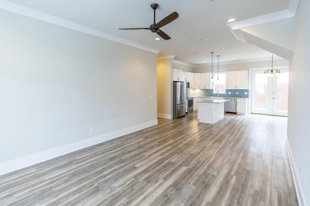 unfurnished living room featuring crown molding, a sink, light wood-style flooring, baseboards, and recessed lighting