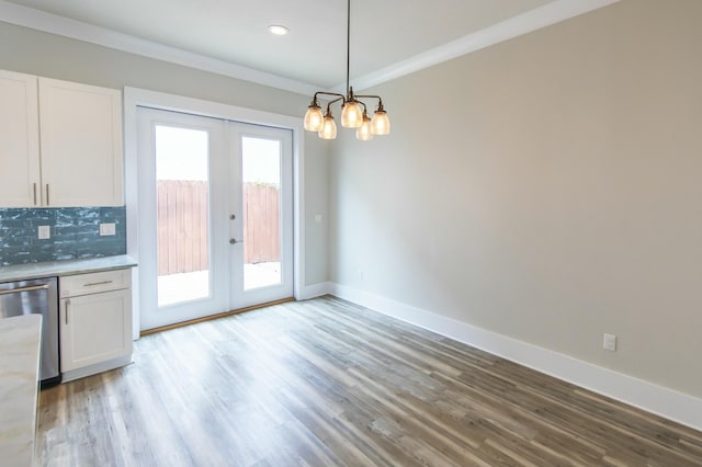 unfurnished dining area with a chandelier, baseboards, french doors, and wood finished floors