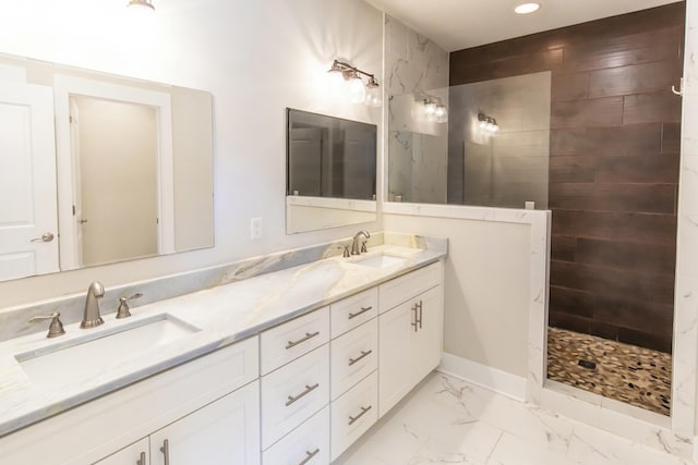 full bathroom with marble finish floor, a sink, double vanity, and a tile shower