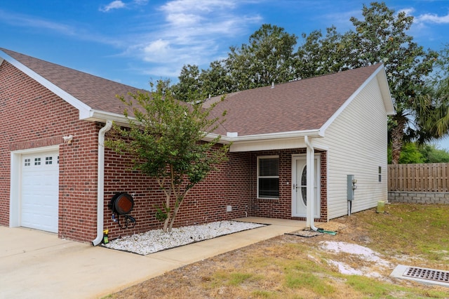 ranch-style home featuring a garage, brick siding, a shingled roof, and fence