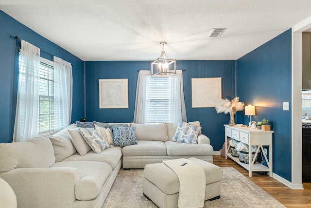 1017 Revere Dr, Pensacola, FL 32505 - living room featuring a chandelier, visible vents, baseboards, a textured ceiling, and wood finished floors