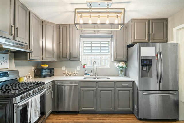 1017 Revere Dr, Pensacola, FL 32505 - kitchen with stainless steel appliances, under cabinet range hood, light countertops, a sink, and gray cabinetry