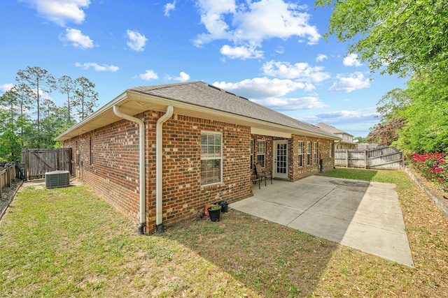 back of house with central AC, a yard, brick siding, and a fenced backyard