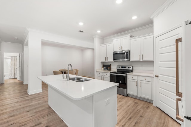 kitchen featuring a sink, appliances with stainless steel finishes, visible vents, light wood finished floors, and ornamental molding