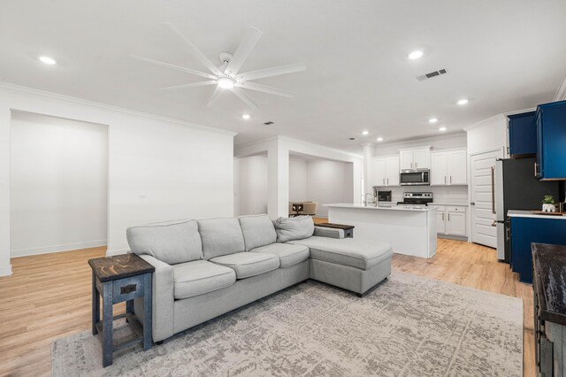 living area with crown molding, light wood finished floors, recessed lighting, and ceiling fan