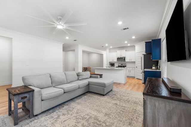 living area featuring visible vents, ceiling fan, light wood-style floors, recessed lighting, and ornamental molding