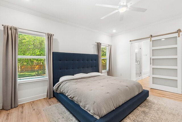 bedroom with a barn door, ornamental molding, wood finished floors, and multiple windows