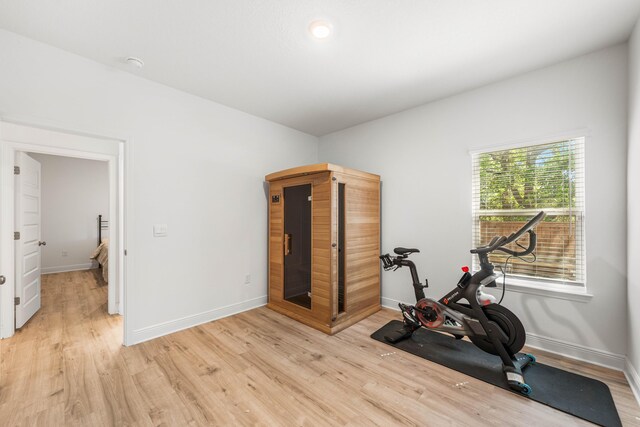 workout room featuring light wood finished floors and baseboards