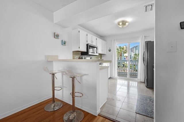 8522 Gulf Blvd Unit 20, Navarre, FL 32566 - kitchen with decorative backsplash, appliances with stainless steel finishes, a peninsula, white cabinetry, and visible vents