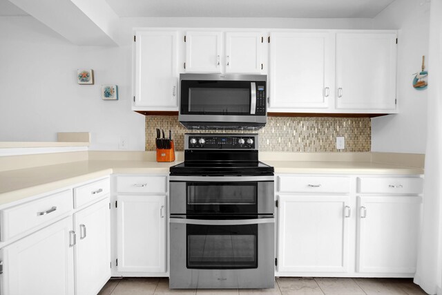 8522 Gulf Blvd Unit 20, Navarre, FL 32566 - kitchen with stainless steel appliances, light countertops, backsplash, light tile patterned floors, and white cabinetry