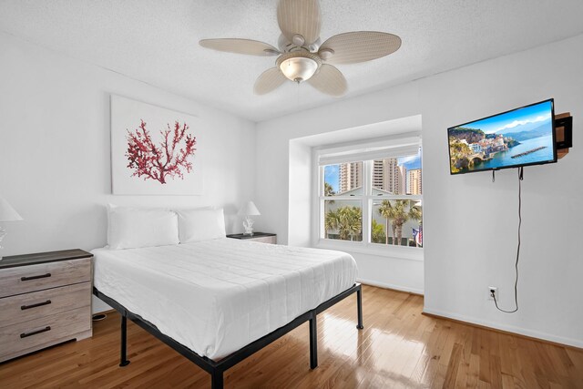 8522 Gulf Blvd Unit 20, Navarre, FL 32566 - bedroom with light wood-style flooring, a textured ceiling, a ceiling fan, and baseboards