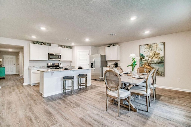 8760 Bluebell St, Milton, FL 32583 - dining area featuring a textured ceiling, light wood-style floors, baseboards, visible vents, and recessed lighting