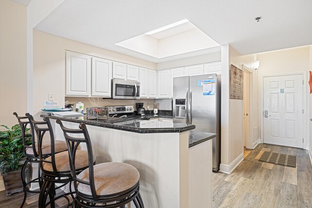 112 Seascape Dr Unit 707, Miramar Beach, FL 32550 - kitchen with a breakfast bar, light wood-style floors, appliances with stainless steel finishes, white cabinets, and a peninsula