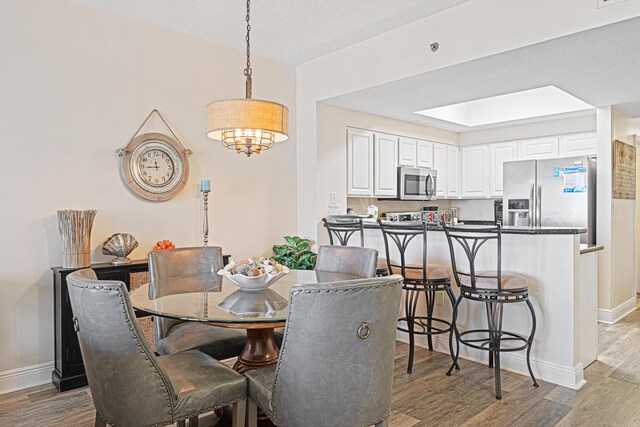 112 Seascape Dr Unit 707, Miramar Beach, FL 32550 - dining space with baseboards, a skylight, a chandelier, and light wood finished floors