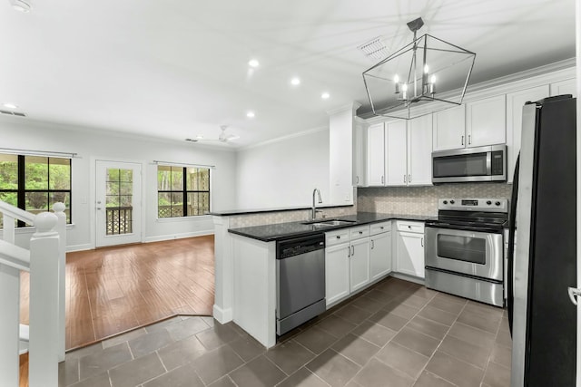 kitchen with a sink, stainless steel appliances, a notable chandelier, ornamental molding, and open floor plan