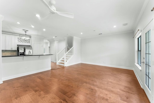 unfurnished living room featuring recessed lighting, wood finished floors, ornamental molding, baseboards, and visible vents
