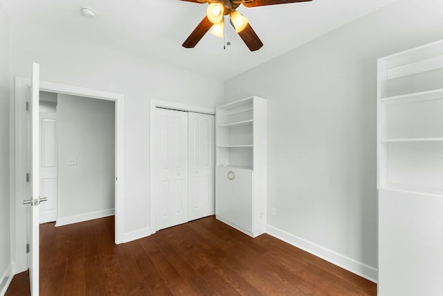 unfurnished bedroom with dark wood-style flooring, ceiling fan, a closet, and baseboards