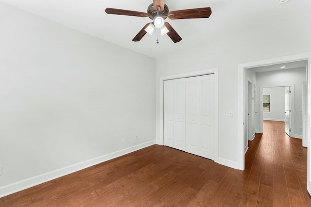 unfurnished bedroom featuring dark wood finished floors, a ceiling fan, a closet, and baseboards