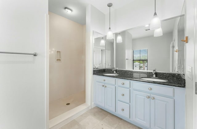 full bath featuring double vanity, tile patterned floors, a shower stall, and a sink