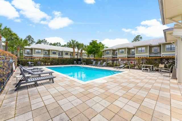 pool featuring fence, a patio, and a residential view