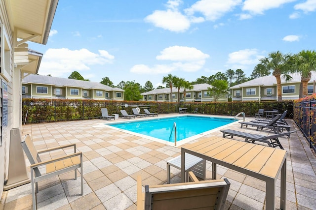 community pool featuring fence, a residential view, and a patio area