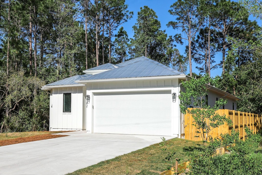 view of front of property featuring board and batten siding, an attached garage, driveway, and metal roof