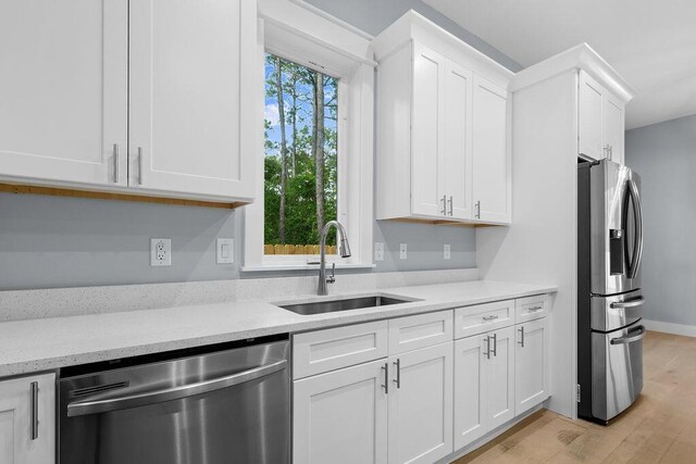 42 Central 8th St, Santa Rosa Beach, FL 32459 - kitchen featuring light stone countertops, white cabinetry, a sink, light wood finished floors, and appliances with stainless steel finishes