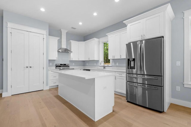 42 Central 8th St, Santa Rosa Beach, FL 32459 - kitchen featuring wall chimney range hood, appliances with stainless steel finishes, a sink, and light wood-style flooring