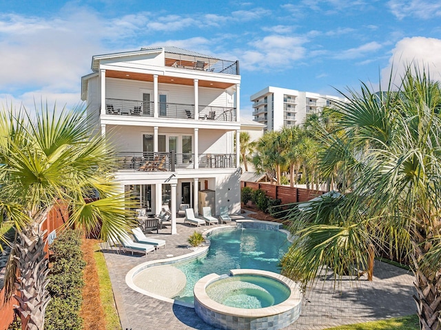 back of house featuring a balcony, a fenced backyard, a patio, and a pool with connected hot tub