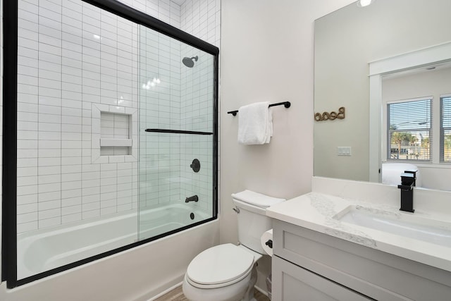 bathroom with combined bath / shower with glass door, toilet, and vanity