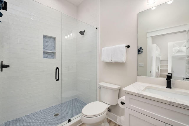 full bath with a stall shower, toilet, and vanity
